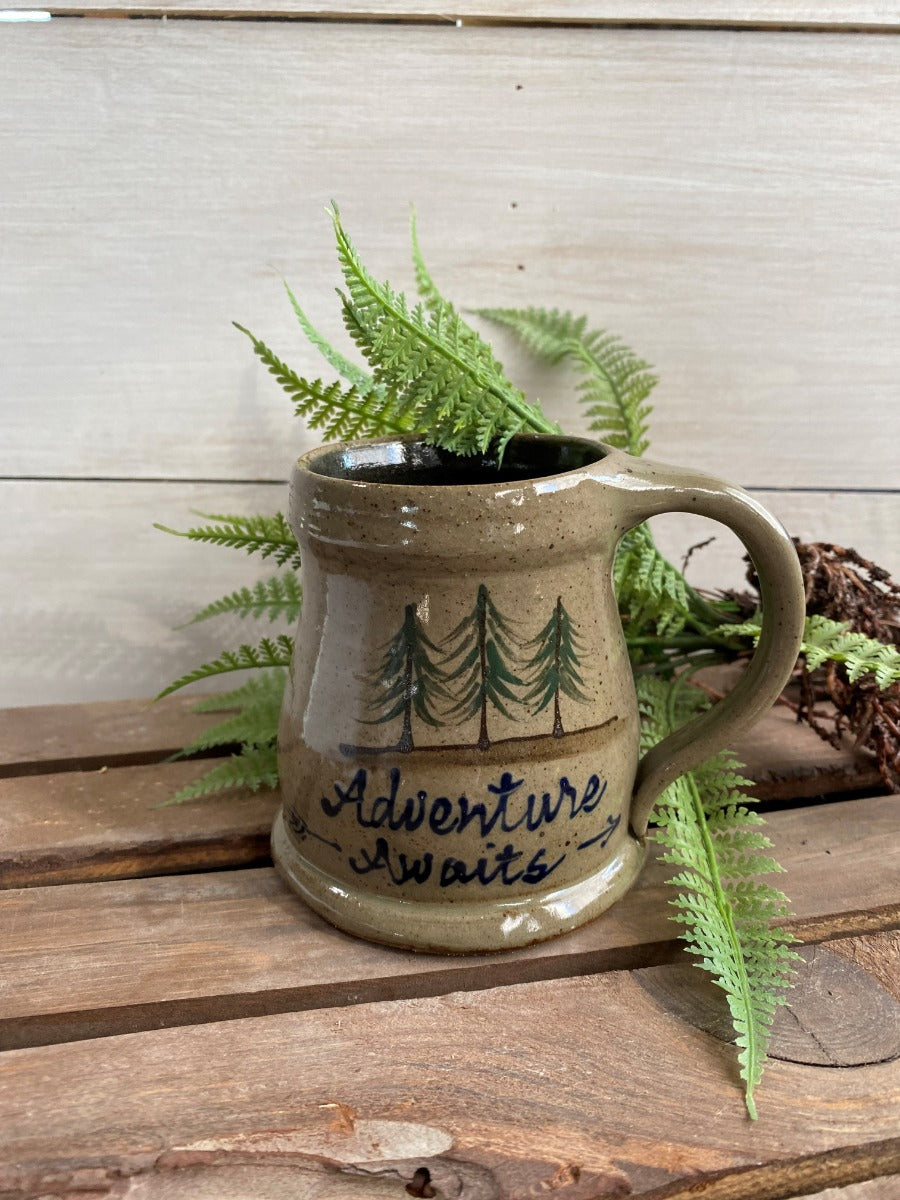 Rowe Pottery Hand thrown stoneware mug In a hand decorated adventure awaits pattern on wooden background with greens