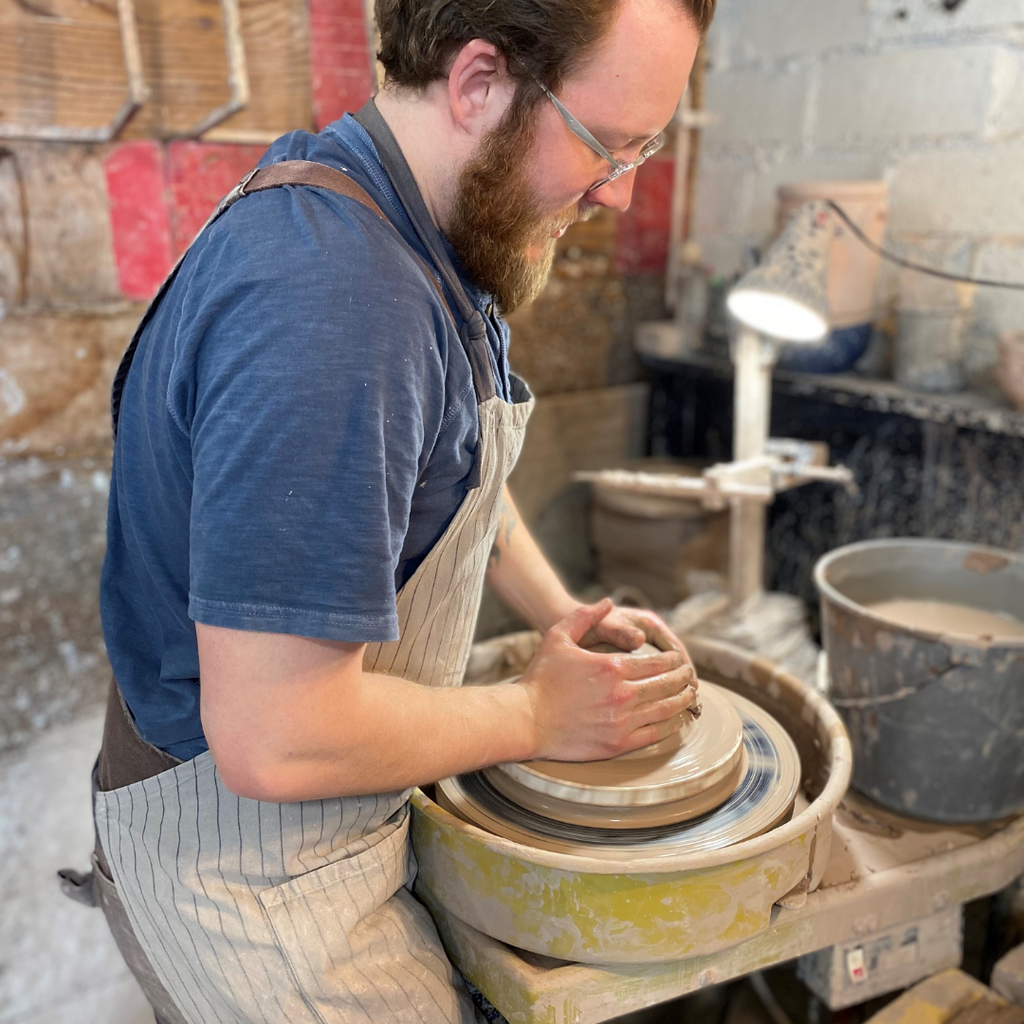 Rowe Pottery potter hand throwing mug on potters wheel