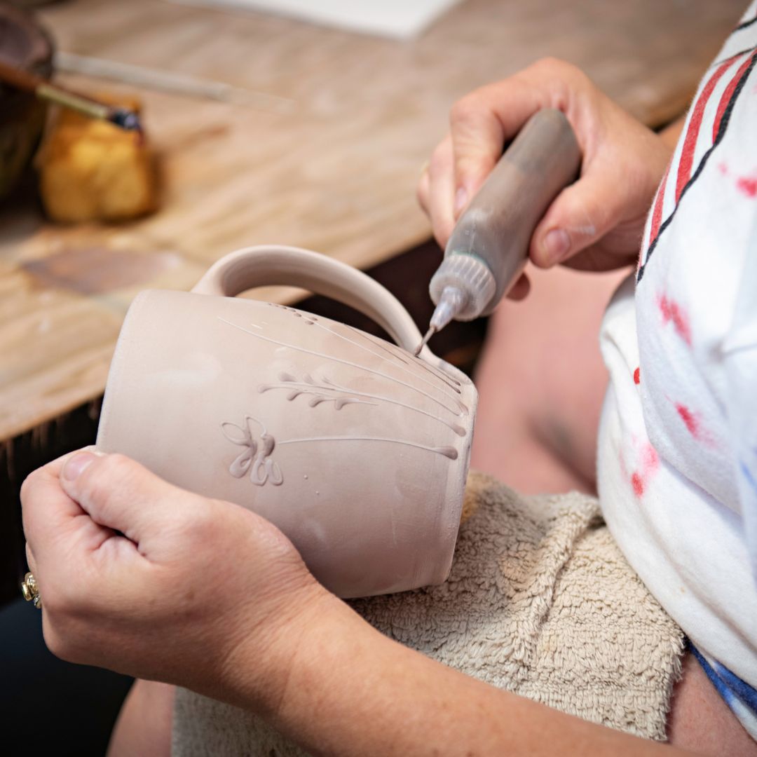 Rowe Pottery Hand thrown stoneware mug In a hand decorated wildflower pattern being decorated 